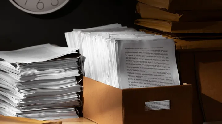Pilhas de documentos e papéis arquivados sob um relógio.